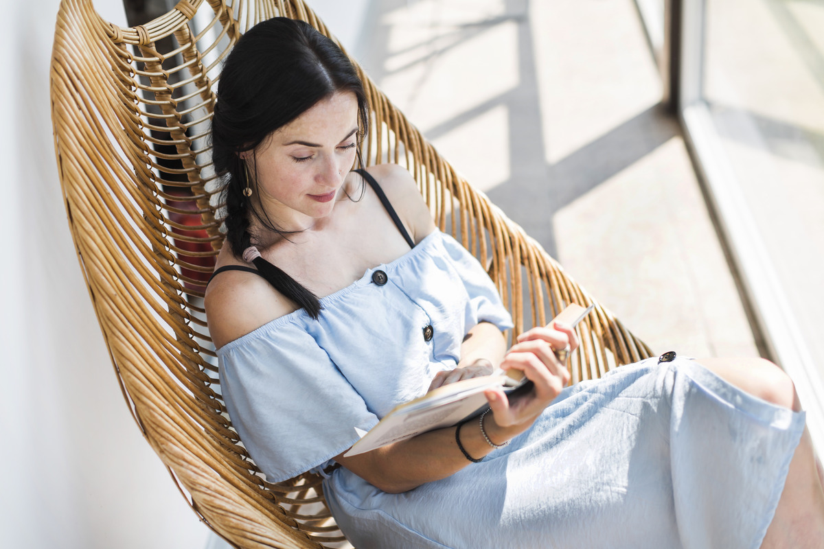overhead-view-woman-sitting-wooden-chair-reading-book