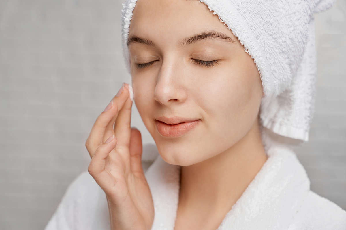 woman-with-closed-eyes-applying-moisturizer-face